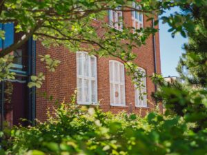 Bild på Sofielunds folkets hus på Rolfsgatan i Malmö, i förgrunden gröna blad