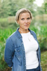 Blond l&auml;rare med tatueringar i gr&ouml;n milj&ouml;